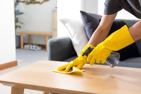 Sanitising surfaces cleaning home table with disinfectant spray with towel and gloves
