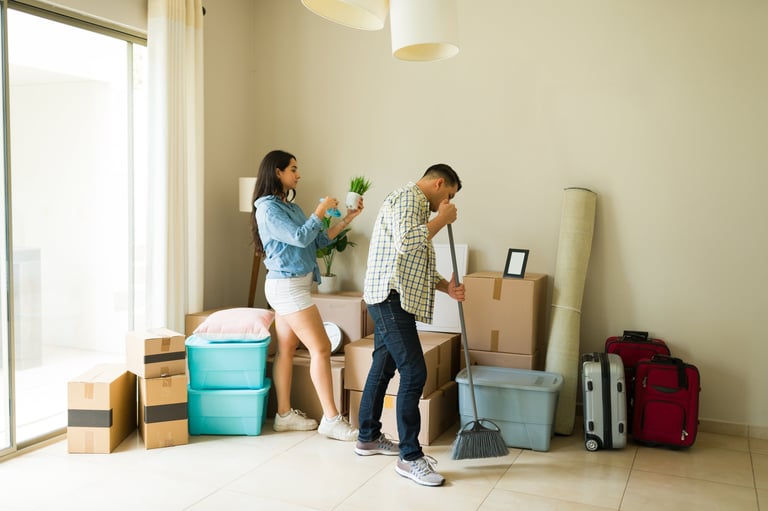 Couple cleaning and moving into new home with boxes and furniture, representing move-in move-out cleaning