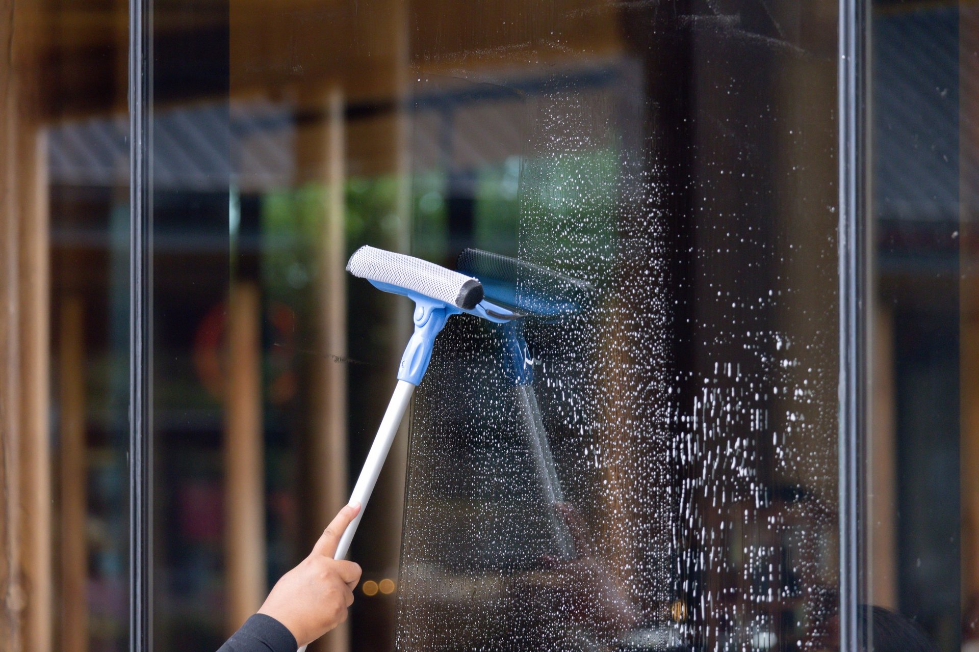 Professional window cleaning with squeegee for streak-free finish on commercial building windows