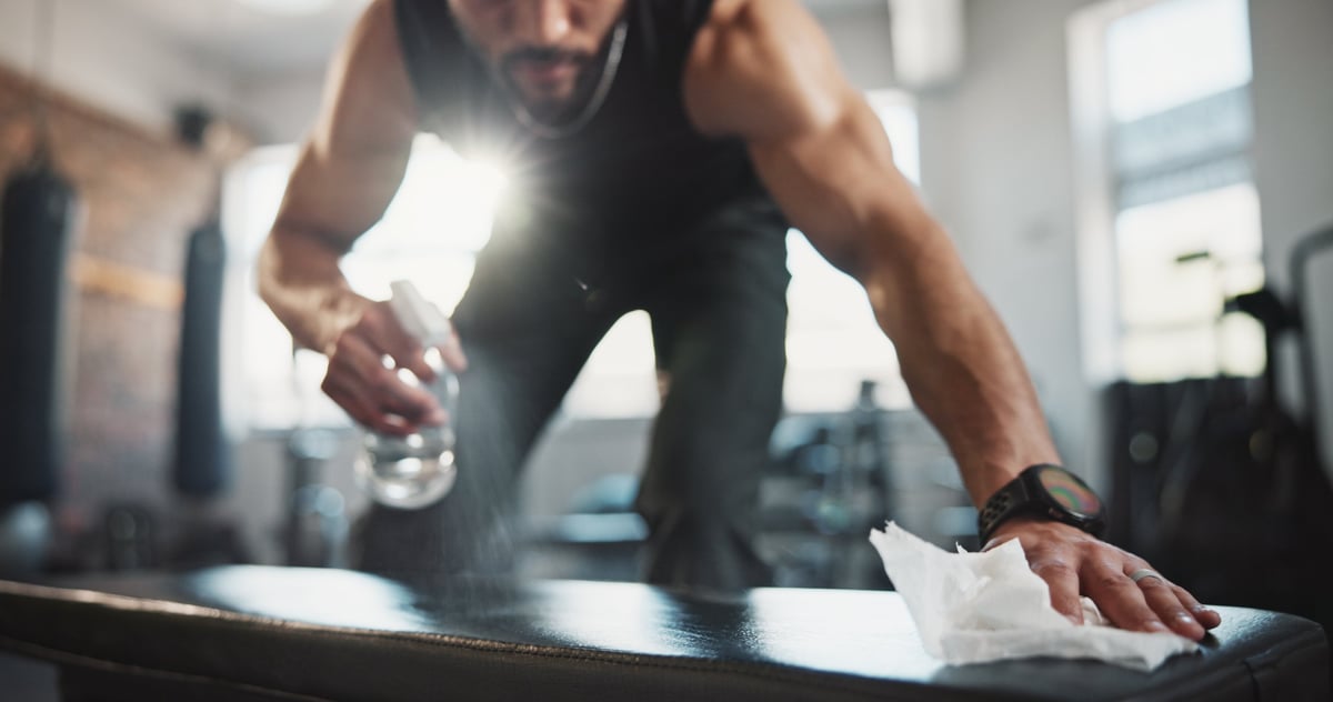 Gym equipment being sanitised and disinfected by a cleaner