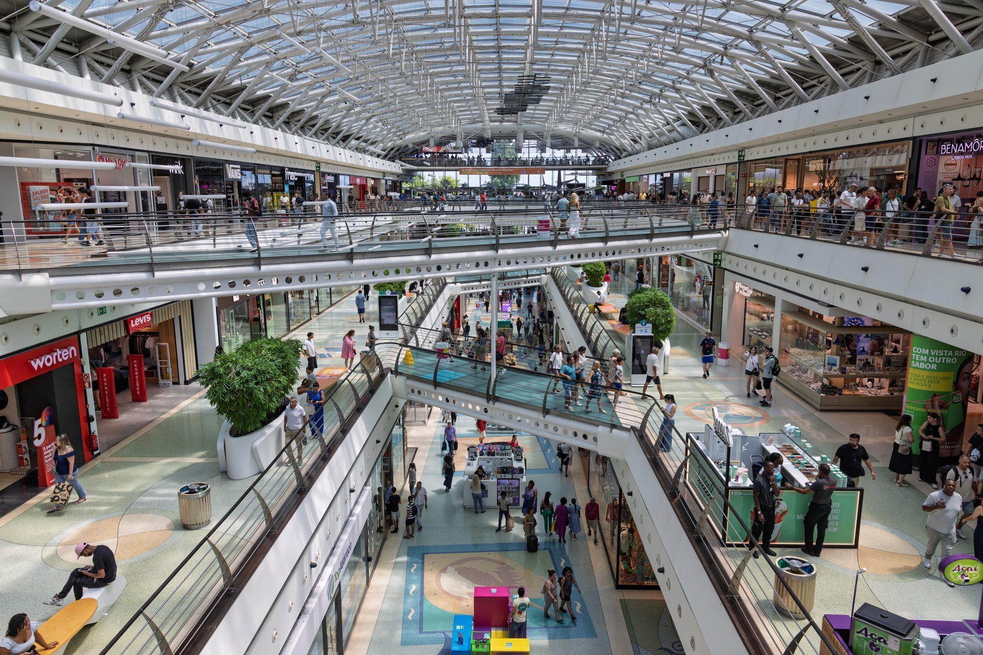 Bright modern shopping mall interior with glass roof and multiple floors