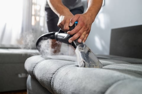 Professional deep cleaning and sanitising sofa upholstery with a steam cleaner