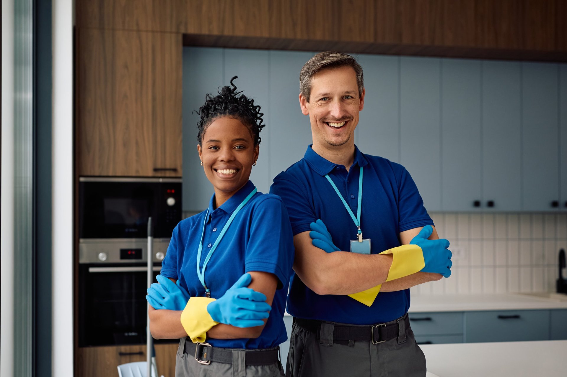 Happy diverse professional cleaners standing with arms crossed and looking at camera