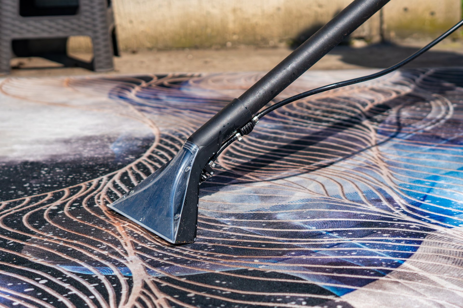 Professional carpet cleaning with extraction vacuum cleaner removing water and dirt from patterned rug