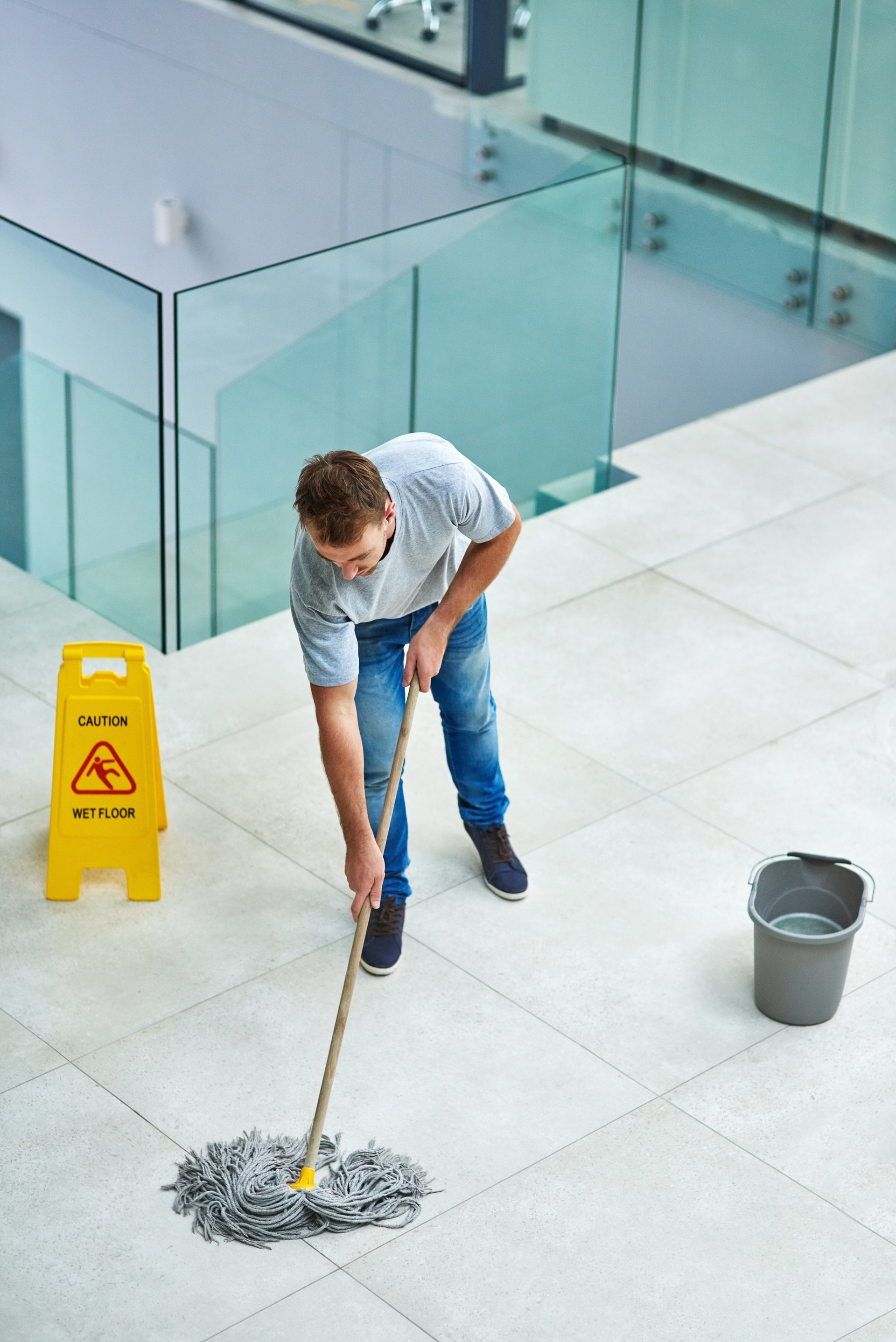 Professional office cleaning with uniformed staff mopping modern office floor